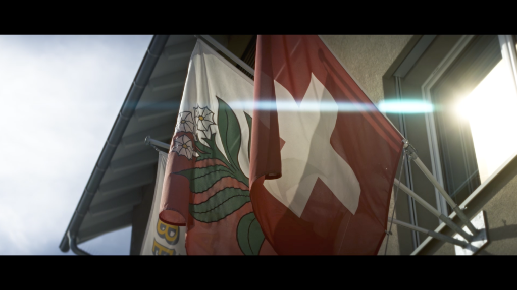 Swiss Flag with a beautiful blues flare reflecting on a window